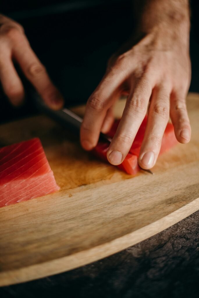 10 Best Chef Knife for Daily Preparation: A Comprehensive Guide Hands expertly slicing fresh tuna on a wooden board, showcasing precision and culinary skill.